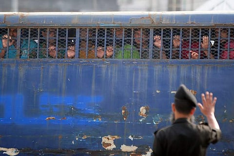 Handcuffed Bangladesh Rifles (BDR) soldiers look through a prison van as they arrive at a huge specially-built court accused of murder and other serious offences during a bloody mutiny in 2009. During the uprising, which lasted about 30 hours, 74 people -