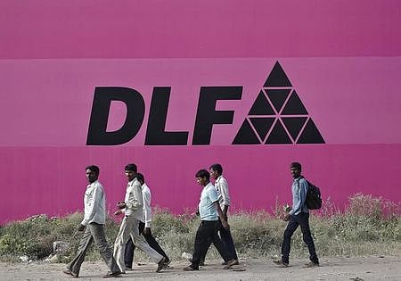 Workers walk past a billboard of DLF Ltd. at Gurgaon in the outskirts of New Delhi. (File photo |  Reuters)