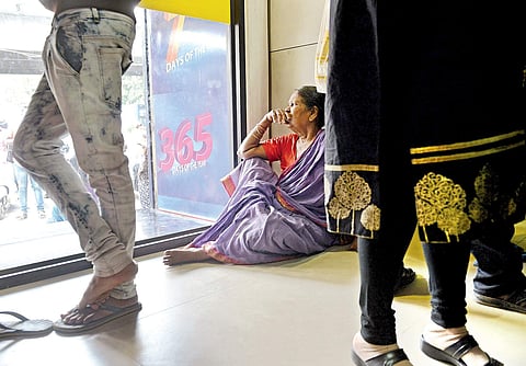 A file picture of an elderly woman sitting on the floor at a bank, when she  had gone to withdraw her pension money.
