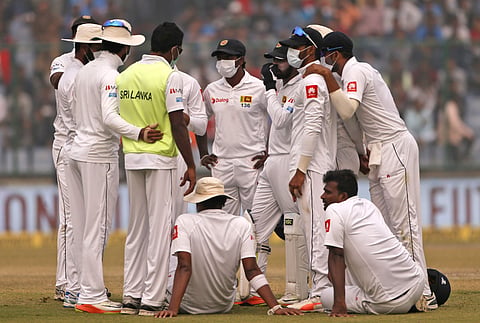 Sri Lanka's players, wearing anti-pollution masks, speak to each other as the game was briefly stopped during the second day of their third Test match in New Delhi, India, Sunday, Dec. 3, 2017. | AP