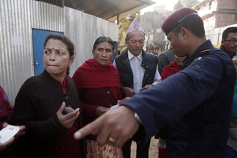 A Nepalese policeman assist voters during the legislative elections | AP