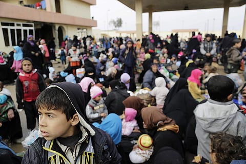 Civilians who fled clashes between Iraqi forces and Islamic State group fighters in Mosul are gathered at an old gas station south of the city.  AP