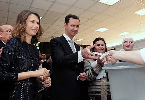 A handout picture made available on the Syrian Presidency Facebook page on April 13, 2016 shows Syrian President Bashar al-Assad (C) and his wife Asma (L) voting at a polling station in Damascus during the parliamentary elections. | AFP