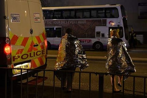 Concert-goers wait to be picked up at the scene of a suspected terrorist attack  in Manchester, northwest England. There were scenes of panic as Grande's audience of youthful fans fled the 21,000-capacity venue after what eyewitnesses described as a 'huge