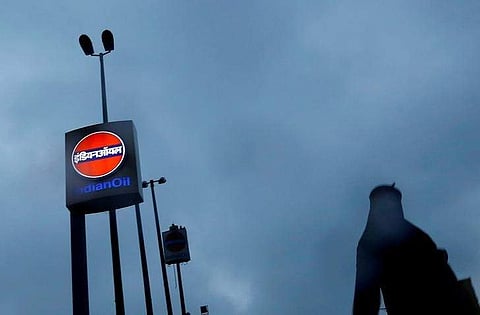 A woman walks past a logo of Indian Oil outside a fuel station in New Delhi.  | Reuters