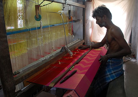 A weaver at work in weaving golden threads into the red silk saree. | EPS/ Ashwin Prasath