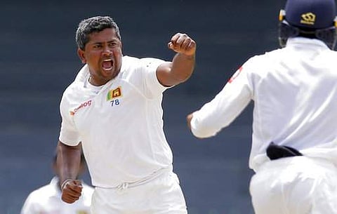 Sri Lanka's Rangana Herath, left, celebrates taking the wicket of Zimbabwe's Hamilton Masakadza during the third day's play of the only test cricket match. | AP