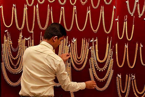 A salesman arranges gold ornaments, on a display board, inside a jewellery showroom during Akshaya Tritiya. (File photo | Reuters)