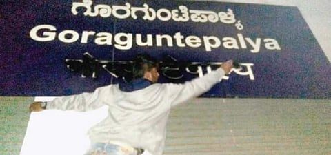 A Metro employee cleaning a blackened name board at Goraguntepalya Metro station in Bengaluru on Thursday.  | Jithendra M