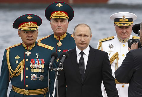 Russian President Vladimir Putin, center, Defence Minister Sergei Shoigu, left, Commander-in-Chief of the Russian Navy Vladimir Korolev, right, and Commander of Western military district Andrei Kartapolov arrive to attend the military parade during the Na