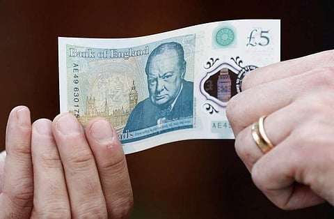 Bank of England governor Mark Carney poses with a new polymer five pound note at Whitecross Street Market in London, Britain September 13, 2016.|REUTERS