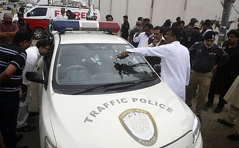 Pakistani officials look at a police vehicle ambushed by unknown gunmen in Karachi (AP)