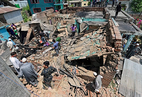 Villagers standing on the debris of a house which was destroyed during a gunbattle between security forces and militants in Hakhri Pora in Pulwama District on Tuesday.  | PTI