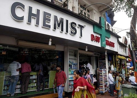 People walk past a chemist shop at a market | REUTERS/Shailesh Andrade