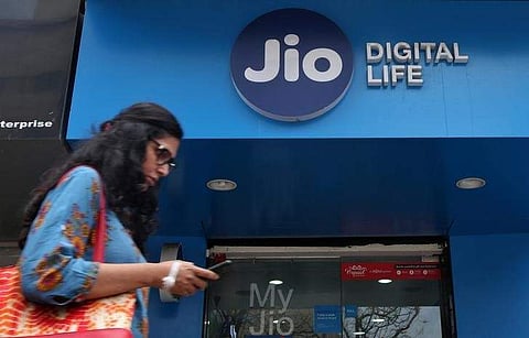 A woman checks her mobile phone as she walks past a mobile store of Reliance Industries' Jio unit in Mumbai.(Photo | Reuters)