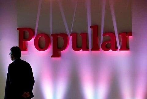 A man stands next to the logo of Spain's Banco Popular during the bank's results presentation in Madrid. (Photo | Reuters)