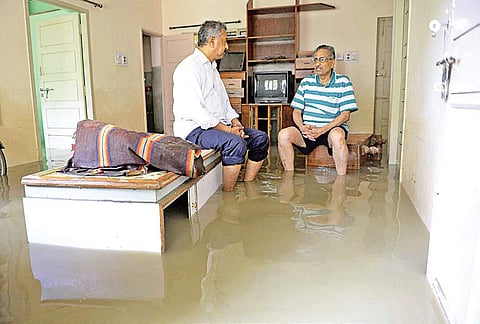 Residents take a break from clearing the water from their home near Maharaja Circle in Koramangala on Saturday