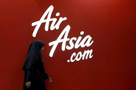 A woman walks past the Air Asia logo at its sales centre in Kuala Lumpur, Malaysia. (File photo | Reuters)