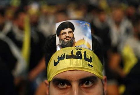 A Hezbollah supporter, wears an Arabic headband that reads:'Hey Quds' with a portrait of Hezbollah leader Sayyed Hassan Nasrallah. 