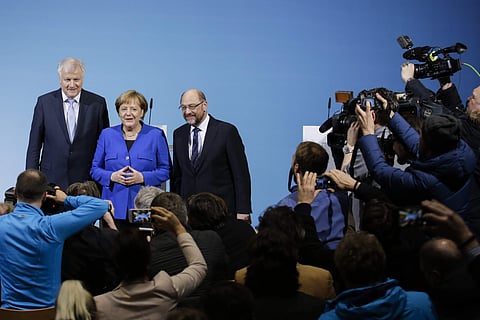 German Chancellor Angela Merkel, center, Bavarian governor Horst Seehofer, left, and Social Democratic Party Chairman Martin Schulz pose for the media after the exploratory talks between Merkel's conservative bloc, and the Social Democrats on forming a ne