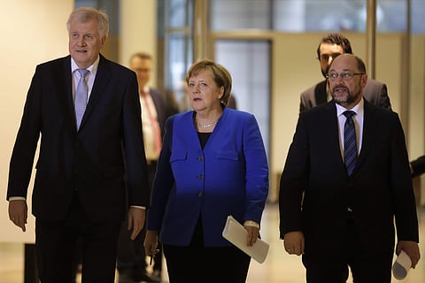 German Chancellor Angela Merkel is flanked by Bavarian governor Horst Seehofer, left, and Social Democratic Party Chairman Martin Schulz after the exploratory talks between Merkel's conservative bloc and the Social Democrats on forming a new German govern