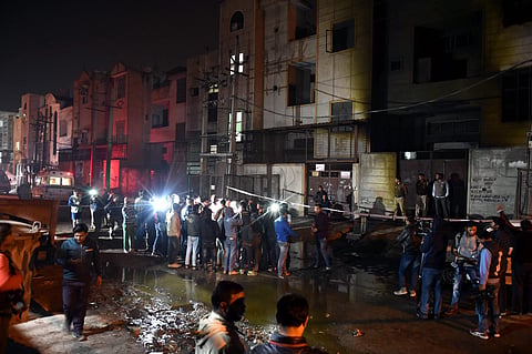 Fire fighters and media outside the two-storey cracker factory which caught fire in north Delhi's Bawana Industrial Area on Saturday. | PTI