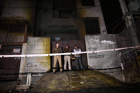 Fire fighters stand outside the two-storey cracker factory which caught fire in north Delhi's Bawana Industrial Area on Saturday. (File | PTI)