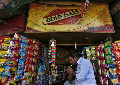 A man lights a cigarette in front of a kiosk in Kolkata. (Photo | Reuters)