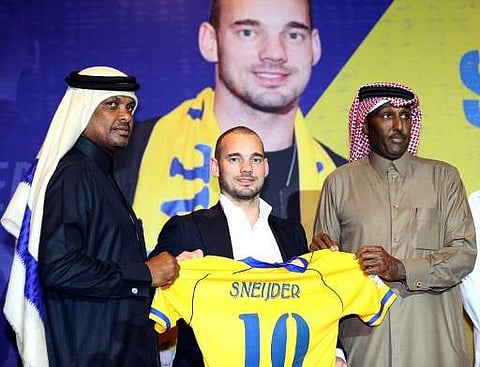 Dutch player Wesley Sneijder (C) poses for a photo with his new jersey during a press conference in Doha as he was officially unveiled by Al-Gharafa football team on January 8, 2018, after signing an 18-month contract with the mid-table Qatari side.  (Pho