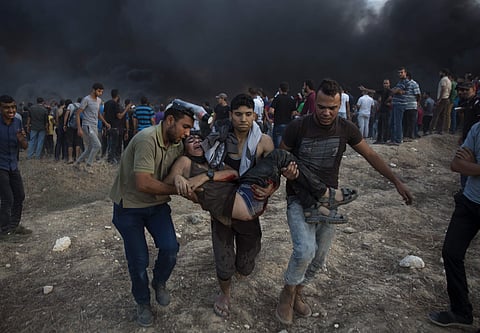 Palestinian protesters evacuate a wounded youth was shot by Israeli troops during a protest at the Gaza Strip's border with Israel. (Photo | AP)