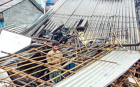 A man repairs his shop which was destroyed by cyclone Titli at Baruva village in Srikakulam district;