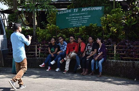 Indian tourists pose beside a sign in the village of Mawlynnong village in the north-eastern state of Meghalaya. (Photo | AFP)