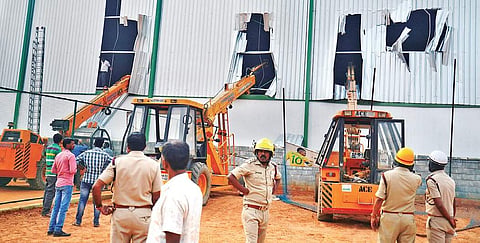 Fire and rescue personnel try to lift a rack from inside the warehouse with the help of cranes at Kadugodi in Bengaluru.