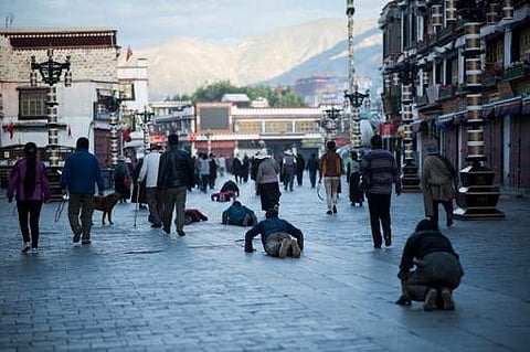 This picture taken on September 11, 2016 shows pilgrims praying and prostrating outside the Jokhang Temple in the regional capital Lhasa, in China's Tibet Autonomous Region.  (AFP)