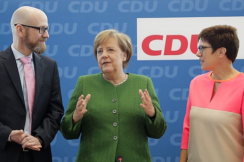 German Chancellor Angela Merkel, center, outgoing Christian Democratic Union party, CDU, Secretary General Peter Tauber, left, and the governor of German Saarland state and designated CDU Secretary General, Annegret Kramp-Karrenbauer, arrive at a party's 