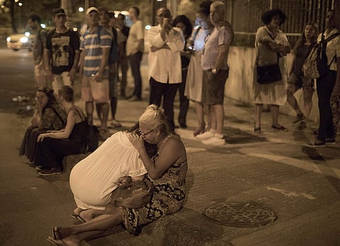 People cry on the sidewalk next to scene where council member Marielle Franco and her driver have where shot to death. (Photo | AP)