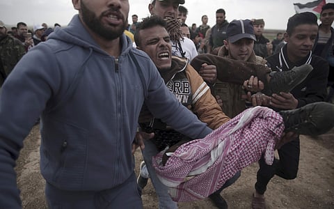Palestinian protesters carry a wounded man who was shot by Israeli troops during a demonstration near the Gaza Strip border with Israel in eastern Gaza City. | AP