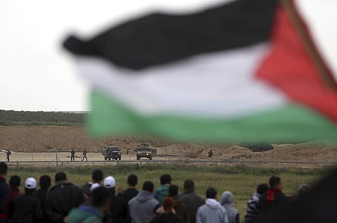 Protesters, one holding a Palestinian flag, stand in front of Israeli soldiers during a demonstration near the Gaza Strip border with Israel, in eastern Gaza City. | AP