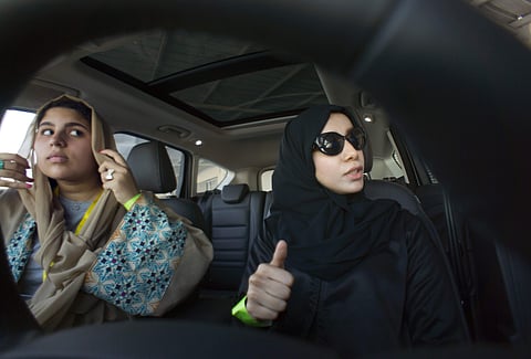Fatima Salem, right, giggles as Sara Ghouth adjusts her veil, during training sponsored by Ford Motor, in Jiddah, Saudi Arabia. | AP
