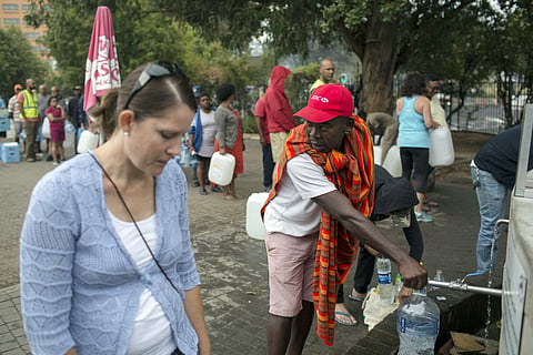 Residents fill containers with water at a source for natural spring water in Cape Town, South Africa (AP)
