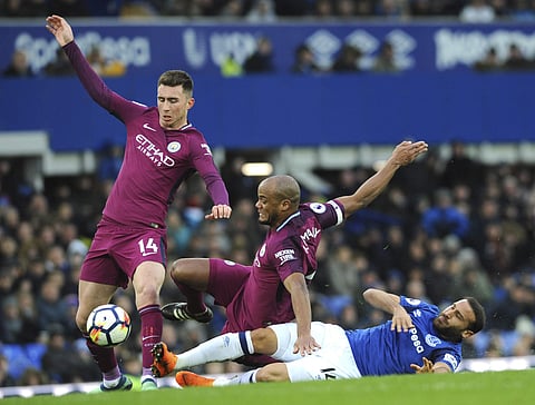 Manchester City's Vincent Kompany, centre, Manchester City's Aymeric Laporte , left, and Everton's Cenk Tosun, right, battle for the ball during the English Premier League soccer match between Everton and Manchester City at Goodison Park in Liverpool, Eng
