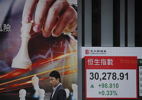 A man walks past an electronic board showing Hong Kong share index outside a local bank in Hong Kong, Wednesday, April 4, 2018. | AP File photo