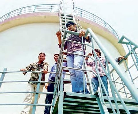 Contract assistant professors climb water tank opposing  APPSC screening test, in Guntur on Friday | Express