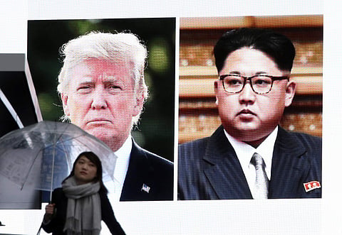 A woman walks by a huge screen showing U.S. President Donald Trump and North Korean leader Kim Jong Un (Photo | AP)