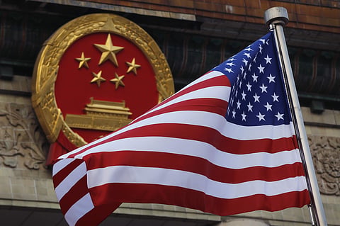 In this Nov. 9, 2017, file photo, an American flag is flown next to the Chinese national emblem during a welcome ceremony for visiting U.S. President Donald Trump outside the Great Hall of the People in Beijing. | Associated Press