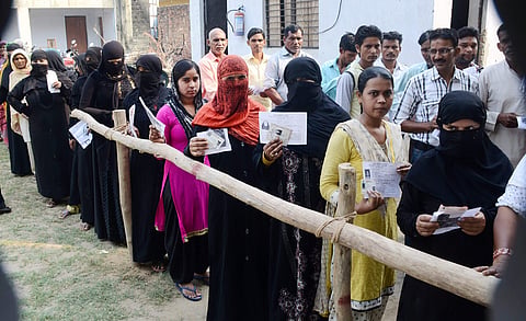 Burqa-clad women along with other voters show their voter identity cards as they wait to cast thier votes for Noorpur Assembly bypolls in Bijnor. (PTI)