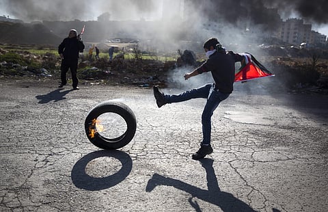 In this file photo, a Palestinian protester kicks a tire following protests against US. President Donald Trump's decision to recognize Jerusalem as the capital of Israel, in the West Bank city of Ramallah, Tuesday, Jan. 9, 2018. (AP Photo/Majdi Mohammed)
