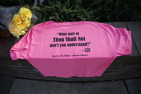 A shirt and flowers rest near the scene of a shooting at The Capital Gazette newspaper office, Friday, June 29, 2018, in Annapolis, Md. A man armed with smoke grenades and a shotgun attacked journalists in the building Thursday, killing several people bef
