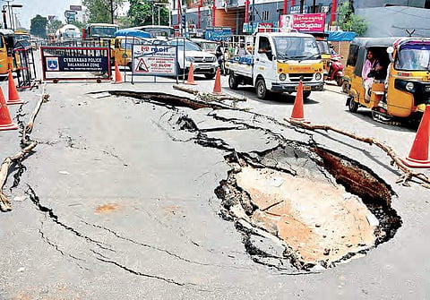 A recently laid BT road caved in at Shapurnagar crossroads, in Hyderabad on Friday. Traffic police  had a tough  time regulating the traffic and diverting hundreds of vechiles through other routes| R Satish Babu