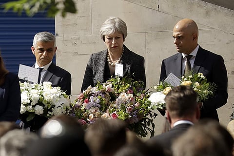 British Prime Minister Theresa May, London mayor Sadiq Khan, left, and British Home Secretary Sajid Javid stand on stage to observe a minute's silence and lay flowers on London Bridge to mark the one year anniversary of the attack that happened there, in 